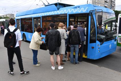 Москва.   Пассажиры садятся в автобус на остановке общественного транспорта.