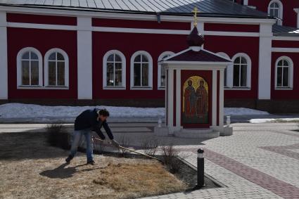 Борисоглебск. Мужчина  убирает территорию храма.