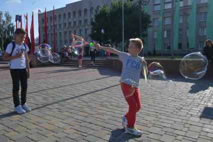 Беларусь, Гродно. Мальчики пускают мыльные пузыри на улице города.
