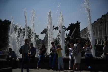 Москва.    Горожане у фонтана `Гейзер` со скульптурой `Времена года` на Манежной площади.