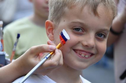 Москва. Мальчику рисуют российский флаг на щеке.