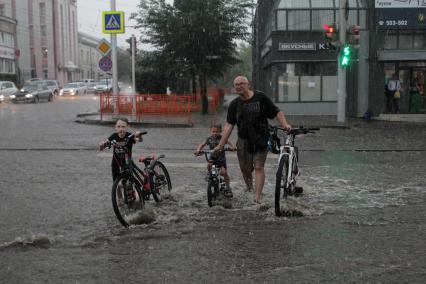 Иркутск.  Мужчина с детьми   во время дождя на одной из улиц города.