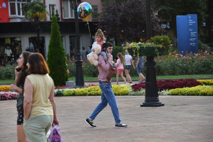 Сочи. Мужчина с девочкой на плечах на улице города.