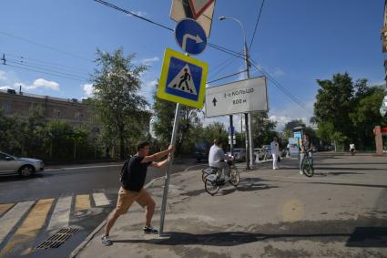 Москва. Корреспондент `Комсомольской правды` Павел Клоков тестирует дорожный знак на гибкой стойке, который при столкновении остается на месте и принимает прежнюю форму.