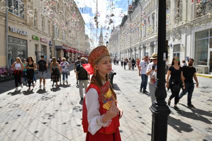 Москва. Девушка в народном костюме раздает рекламные листовки на Никольской улице.