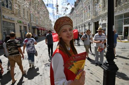 Москва. Девушка в народном костюме раздает рекламные листовки на Никольской улице.