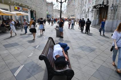 Москва. Мужчина спит на лавочке на Никольской улице.