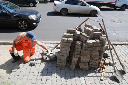 Красноярск.  Рабочий укладывает тротуарную плитку на одной из улиц города.