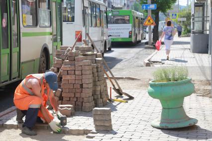 Красноярск.  Рабочий укладывает тротуарную плитку на одной из улиц города.