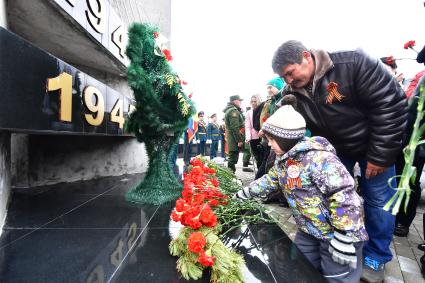 Остров Итуруп, Курильск. Мужчина с ребенком возлагает цветы к мемориалу  в день празднования 73-й головщины Победы в Великой Отечественной войне.