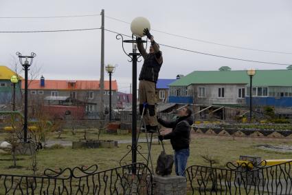 Остров Итуруп, Курильск. Рабочие меняют плафоны на фонарях в городском сквере.