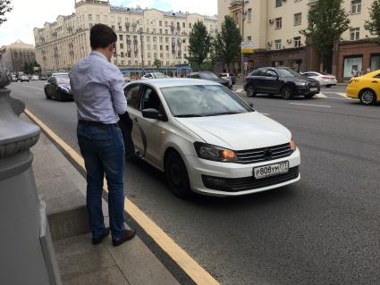 Москва.  Мужчина останавливает частный автомобиль на Тверской улице.