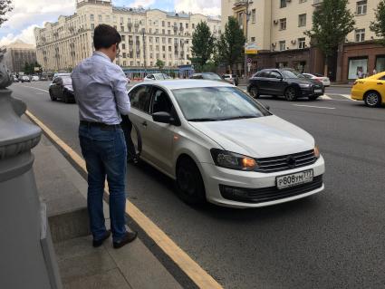 Москва.  Мужчина останавливает частный автомобиль на Тверской улице.