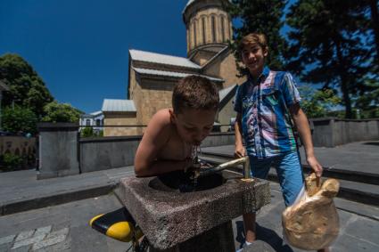 Грузия. Тбилиси.  Мальчик пьет воду у храма Сиони.