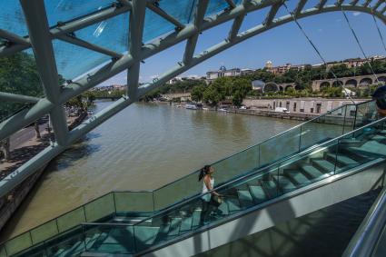 Грузия, Тбилиси.  Пешеходный стеклянный мост Мира через реку Кура (Мтквари).