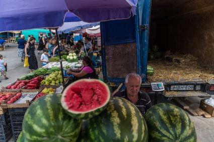 Грузия, Тбилиси.  Мужчина продает арбузы на рынке.