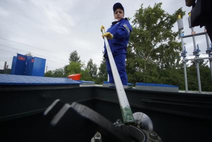 Екатеринбург. Оператор АЗС проверяет металлическим щупом наличие воды в топливном резервуаре на автозаправочной станции \'Газпромнефть\'