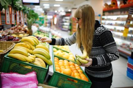 Ставрополь.  Девушка выбирает бананы в магазине.