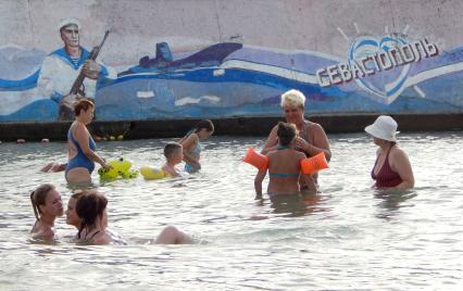 Севастополь. Отдыхающие плавают в море у пляжа `Солнечный`.