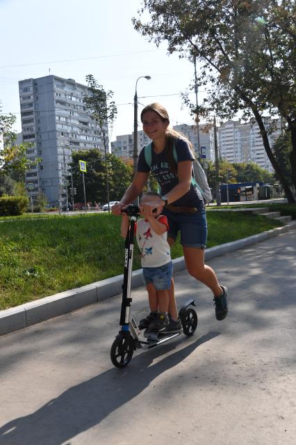 Москва.  Дети катаются на самокате.