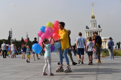 Москва. Девушка на роликовых коньках раздает воздушные шарики.