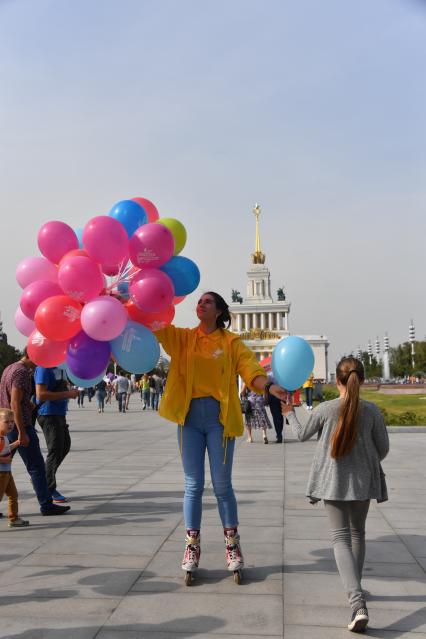 Москва. Девушка на роликовых коньках раздает воздушные шарики.