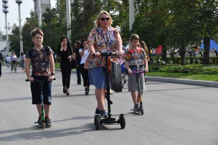 Москва. Женщина с мальчиками на самокатах.