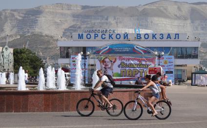 Новороссийск.  Мужчина с девушкой на велосипедах у Морского вокзала.