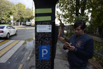 Москва. Мужчина оплачивает парковку автомобиля через паркомат.