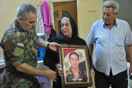 Сирия.  Семья погибшего на войне сирийца с его портретом.
