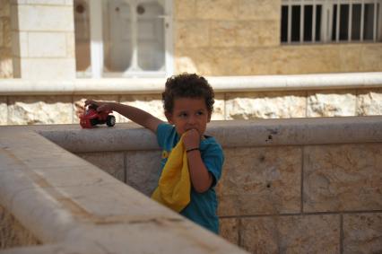 Сирия, Маалюл. Мальчик играет у стен восстановленного после захвата и разрушения боевиками храма в Маалюла.