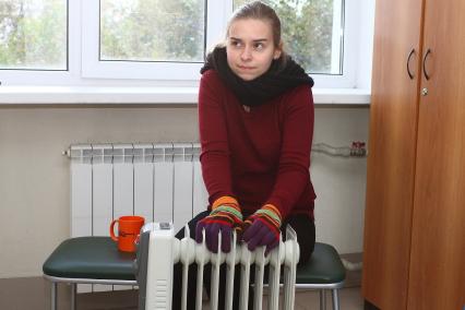 Нижний Новгород. Девушка греется у батареи в холодной квартире.