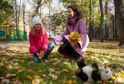 Пермь. Женщина с девочкой в парке собирают осенние листья.