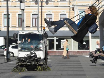 Москва. Девушка качается на качелях.