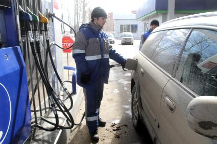 Иркутск.   Сотрудник автозаправочной станции заправляет автомобиль.