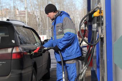 Иркутск.   Сотрудник автозаправочной станции заправляет автомобиль.