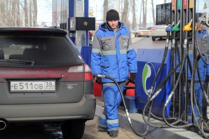 Иркутск.   Сотрудник автозаправочной станции заправляет автомобиль.