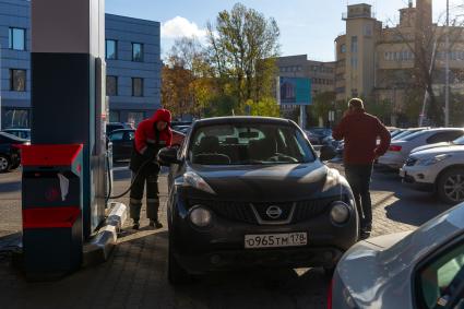 Санкт-Петербург. Сотрудник АЗС заправляет автомобиль на автозаправочной станции.