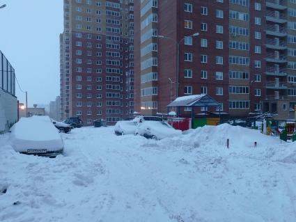 Красноярск.  Занесенные снегом машины на стоянке во дворе дома.