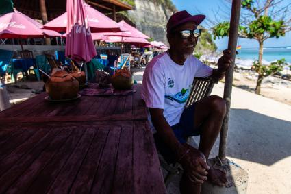 Индонезия, остров Бали, Денпасар. Мужчина в кафе на пляже.