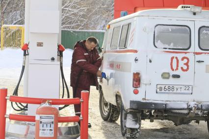 Барнаул. Водитель  заправляет машину скорой помощи на автозаправочной станции.