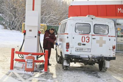 Барнаул. Водитель  заправляет машину скорой помощи на автозаправочной станции.