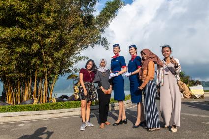 Индонезия, остров Бали. Российские стюардессы фотографируются  с местными жительницами у храма Пура Улун Дану.