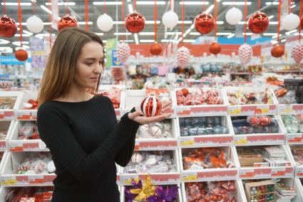 Самара. Девушка выбирает новогодние игрушки в магазине.