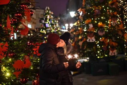 Москва.  Молодые люди среди елок, украшенных к Новому году, на Кузнецком мосту.