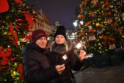 Москва.  Молодые люди среди елок, украшенных к Новому году, на Кузнецком мосту.