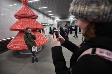 Москва. Пассажиры у елки, сделанной из использованных билетов `Единый`в вестибюле станции `Тургеневская`московского метрополитена.