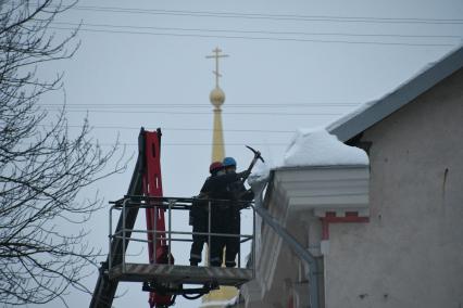 Тула.  Рабочие сбивают сосульки с крыши дома.