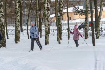 Санкт-Петербург.  Женщина с ребенком катаются на лыжах в парке `Сосновка`.