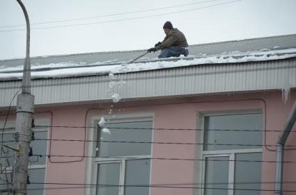 Тула. Сотрудник коммунальных служб счищает снег с крыши.